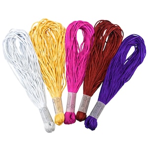 May include: Five bundles of colorful craft thread in white, gold, pink, burgundy, and purple. Each bundle is neatly wrapped with a paper label. The threads are tightly wound, suggesting they are new and ready for use in various crafting projects.