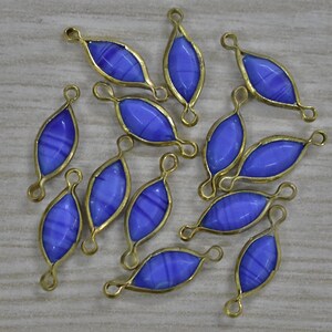 May include: A collection of blue and gold-colored jewelry components. Each component features a blue, oval-shaped glass insert with white stripes, encased in a gold-colored metal frame. The components have loops at both ends for attachment.