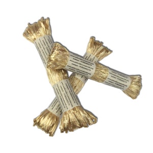 Può includere: Tre bobine di filo da ricamo metallico dorato. Le bobine sono avvolte in carta marrone con il testo "www.embroiderymaterial.com" e "contatto: +918826002179" stampato su di esse.