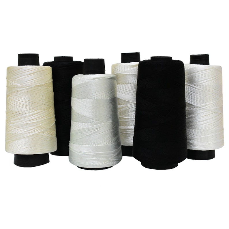May include: A set of six spools of thread, three white and three black. The spools are arranged in a row, with the white spools on the left and the black spools on the right.