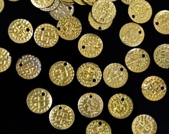 May include: A scattering of gold-colored metal round decorative pieces with a raised design on a black background.