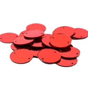 May include: A pile of red oval-shaped mirror tiles with two small holes in each tile.