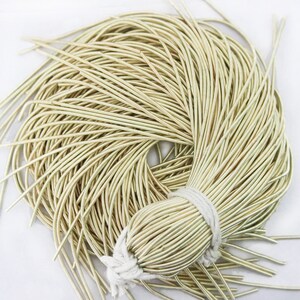 May include: A bundle of gold-coloured wire, approximately 91 metres long, is wrapped in a white string. The wire is thin and flexible, ideal for jewellery making or other crafts.