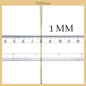 May include: A close-up of a gold chain measured against a ruler. The chain is 1 mm thick.