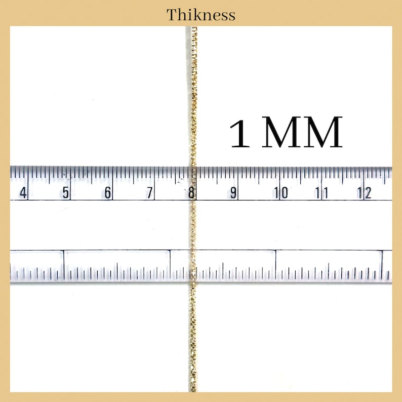 May include: A close-up of a gold chain measured against a ruler. The chain is 1 mm thick.