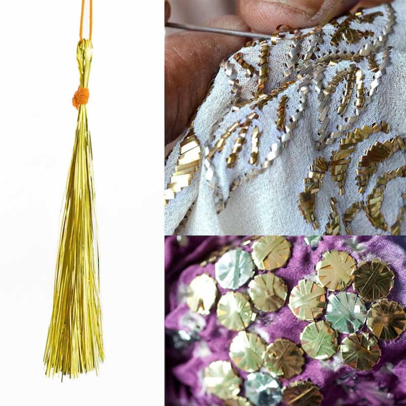 May include: A close-up of gold tassel trim with a gold cord. The tassel is made of thin, shiny strands of gold thread. The cord is tied in a knot at the top of the tassel. The tassel is on a white background.