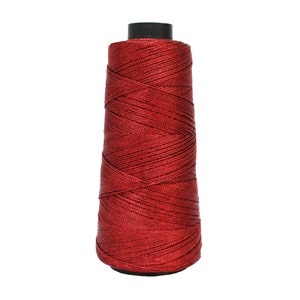 May include: A spool of red thread, ideal for sewing and crafting projects. The thread is tightly wound around a black core, creating a conical shape. The thread has a shiny, metallic appearance.