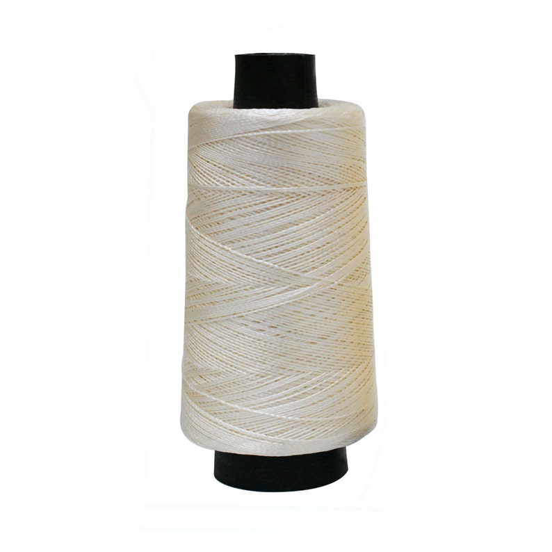 May include: A spool of white thread with a black plastic bobbin.