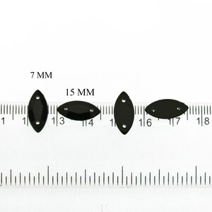 K&ouml;nnte beinhalten: Drei schwarze, ovale Pailletten mit jeweils zwei L&ouml;chern, gemessen an einem Lineal. Die Pailletten sind 7 mm, 15 mm und 15 mm gro&szlig;.