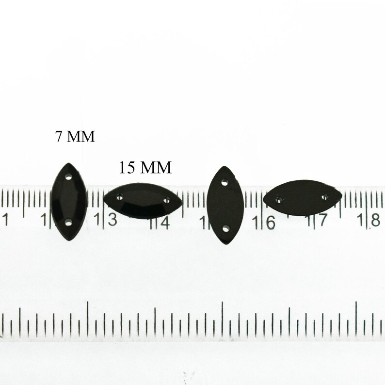 K&ouml;nnte beinhalten: Drei schwarze, ovale Pailletten mit jeweils zwei L&ouml;chern, gemessen an einem Lineal. Die Pailletten sind 7 mm, 15 mm und 15 mm gro&szlig;.