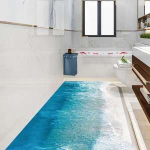 May include: A modern bathroom with white marble walls and a blue and white ocean-themed floor. The bathroom features a white bathtub, a white sink with a wooden vanity, and a large mirror.