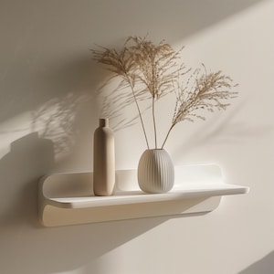 Minimalist 3D printed wall shelf in matte white, holding decorative vases and dried plants, mounted on a softly lit modern wall