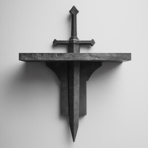Può includere: Una mensola a forma di spada grigio scuro. La mensola presenta un design a spada, con la lama che si estende verso il basso e l'elsa che sostiene la mensola. La mensola è montata su una parete bianca.