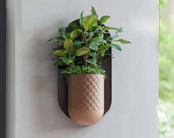 Könnte beinhalten: Ein brauner, wandmontierter Pflanzer mit strukturierter Oberfläche beherbergt eine grüne Pflanze mit üppigem Laub. Der Pflanzer ist oval geformt und hat ein modernes Design.