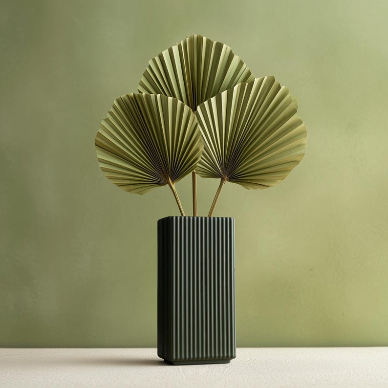 Tall rectangular 3D printed vase with vertical ribbed grooves in dark green color, shown with dried palm leaves for illustration; flowers are not included.