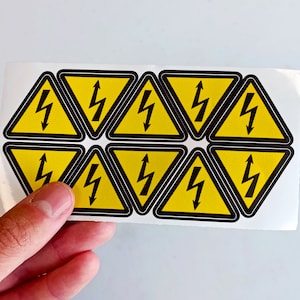 May include: A sheet of yellow warning stickers with a black lightning bolt symbol. The stickers are arranged in a honeycomb pattern.