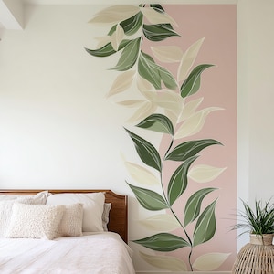 May include: A bedroom wall mural featuring a botanical design. The mural showcases a vertical arrangement of stylized leaves in shades of green and cream against a pink and white background. The bed has a wooden headboard and white bedding.
