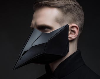 May include: A black, geometric mask with sharp angles and a pointed beak-like design. The mask covers the lower half of the face and is worn by a person in a black coat. The mask has a futuristic, cyberpunk aesthetic.