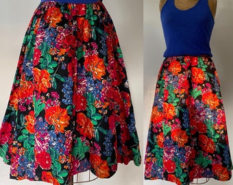May include: A black skirt with a colorful floral print. The skirt is full and has a gathered waist. The flowers are red, orange, yellow, pink, blue, and green.