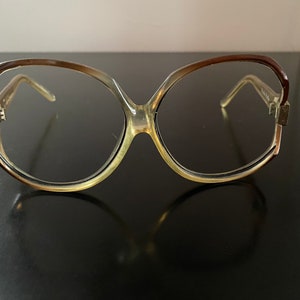 May include: A pair of large, round, brown and clear plastic framed eyeglasses.