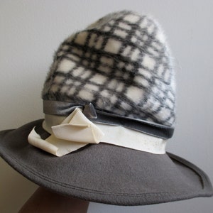 May include: A gray felt hat with a wide brim and a black and white patterned crown. The hat has a white ribbon with a bow and a gray velvet band.