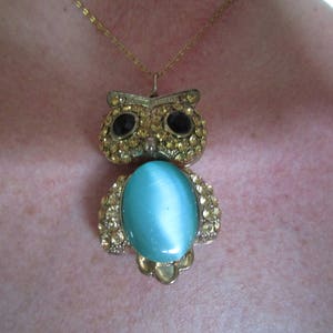 Pu&ograve; includere: Una collana con un ciondolo a forma di gufo in oro e una pietra preziosa blu. Il gufo &egrave; decorato con strass.