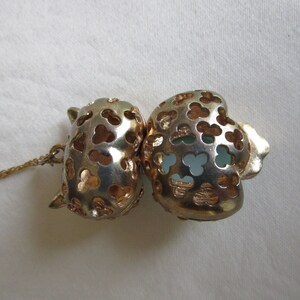 Pu&ograve; includere: Una collana dorata con un ciondolo a forma di due cuori collegati. I cuori sono traforati e presentano un delicato design floreale. Il ciondolo &egrave; impreziosito da una pietra blu chiaro.