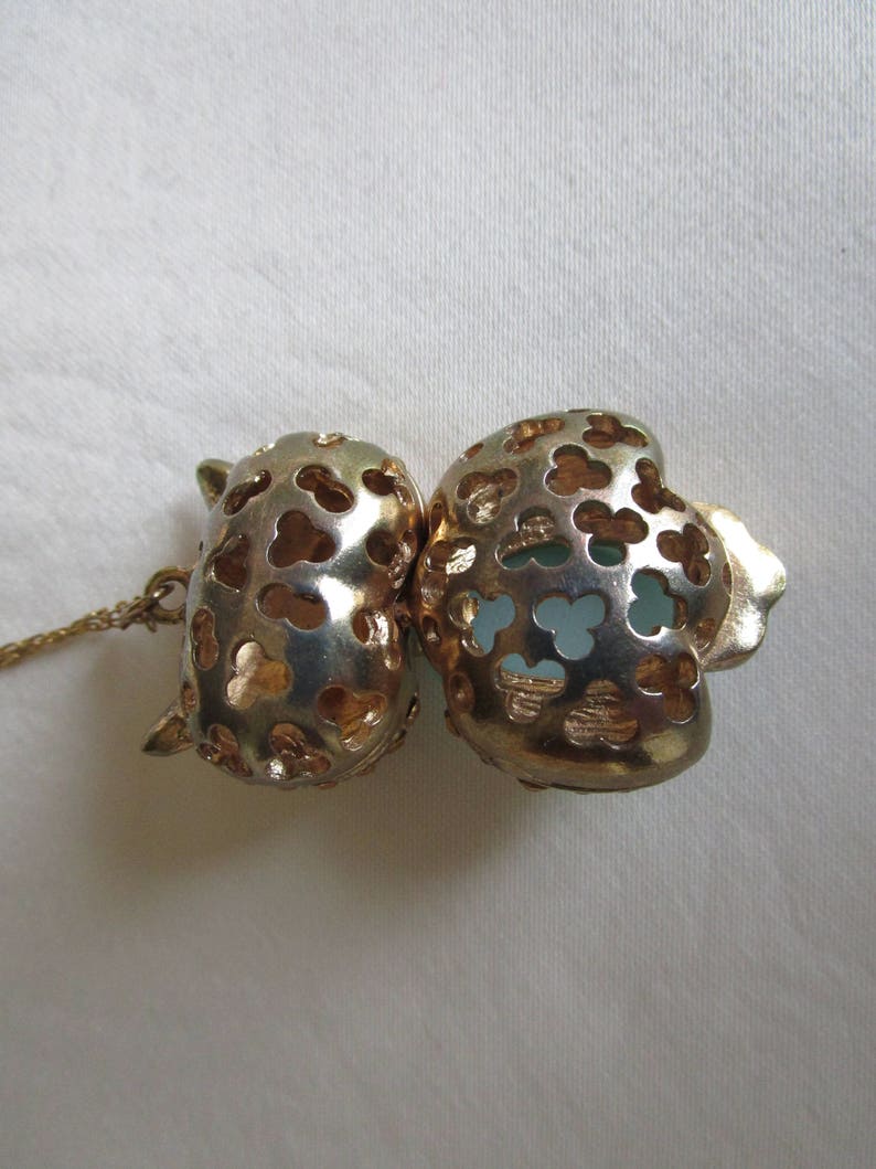 Pu&ograve; includere: Una collana dorata con un ciondolo a forma di due cuori collegati. I cuori sono traforati e presentano un delicato design floreale. Il ciondolo &egrave; impreziosito da una pietra blu chiaro.