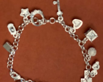 May include: A silver charm bracelet with a variety of charms, including a star, a key, a heart, a house, a golf ball, and a cross.