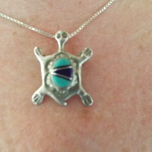 Op de afbeelding: Een zilveren schildpad hanger ketting met een turquoise en blauwe steen inlay. De ketting is aan een zilveren ketting.