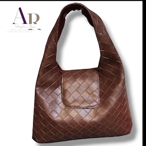 May include: A brown leather shoulder bag with a woven pattern. The bag has a single strap and a flap pocket on the front. The interior lining is a darker shade of red. The bag is a medium size.