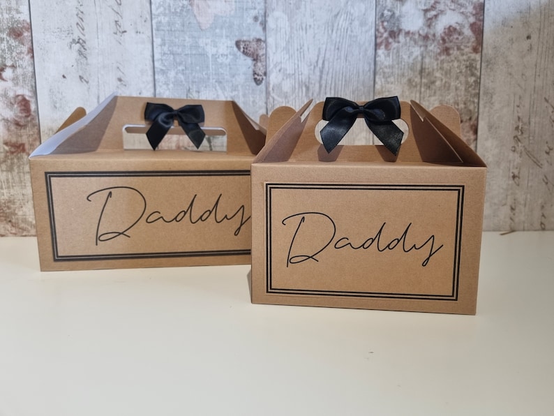 May include: Two brown cardboard gift boxes with black ribbon bows and the word "Daddy" printed on the front.