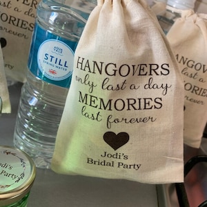 May include: A small white fabric bag with a black heart and the text "Hangover's only last a day Memories last forever" and "Jodi's Bridal Party".