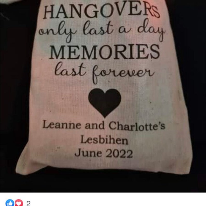 May include: A white fabric bag with black text that reads "Hangover's only last a day Memories last forever" with a black heart in the center. Below the text is "Leanne and Charlotte's Lesbihen June 2022".