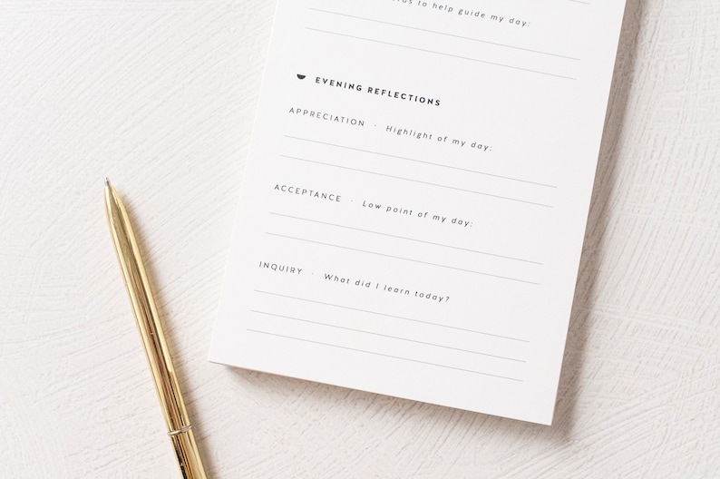 May include: A white journal with a black pen lying on top. The journal has a section titled "Evening Reflections" with prompts for appreciation, acceptance, and inquiry.