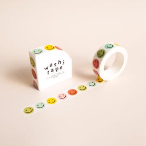 May include: White box and roll of washi tape with colorful smiley faces. The box has the words "washi tape worthwhile paper" printed on it. A strip of tape with smiley faces is unrolled.