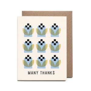 May include: A cream-colored greeting card with a geometric floral pattern in blue, black, and yellow-green. The words "MANY THANKS" are printed in black at the bottom. The card is paired with a brown envelope.