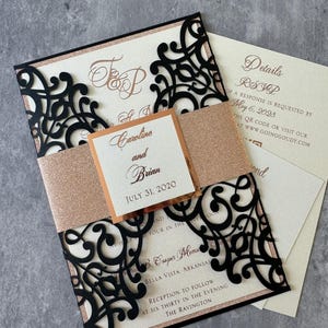 May include: Black and rose gold wedding invitation with a laser cut design. The invitation features the couple's names, "Carolins and Brian", and the wedding date, "July 31, 2020".