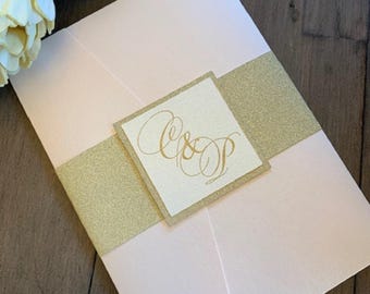 May include: A pink wedding invitation with a gold glitter band and a white square with the initials "C & D" in gold calligraphy.