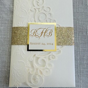 May include: White wedding invitation with a gold glitter band and a gold square with the initials "HB" and the date "August 24, 2024".