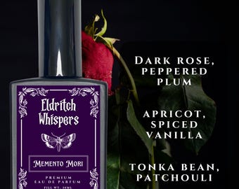 May include: A rectangular perfume bottle with a black cap and a purple label featuring the text Eldritch Whispers, Memento Mori, and Premium Eau de Parfum, 30ml. The label includes a moth illustration and text listing dark rose, peppered plum, apricot, spiced vanilla, tonka bean, and patchouli.