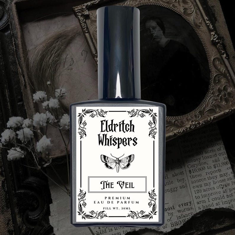 K&ouml;nnte beinhalten: Ein rechteckiger Glasparf&uuml;mflakon mit dunklem Verschluss und wei&szlig;em Etikett. Das Etikett zeigt den Text Eldritch Whispers, eine Mottenillustration und den Text The Veil, Premium Eau de Parfum, Fill Wt. 30ml, umrahmt von schwarzem Dekor.