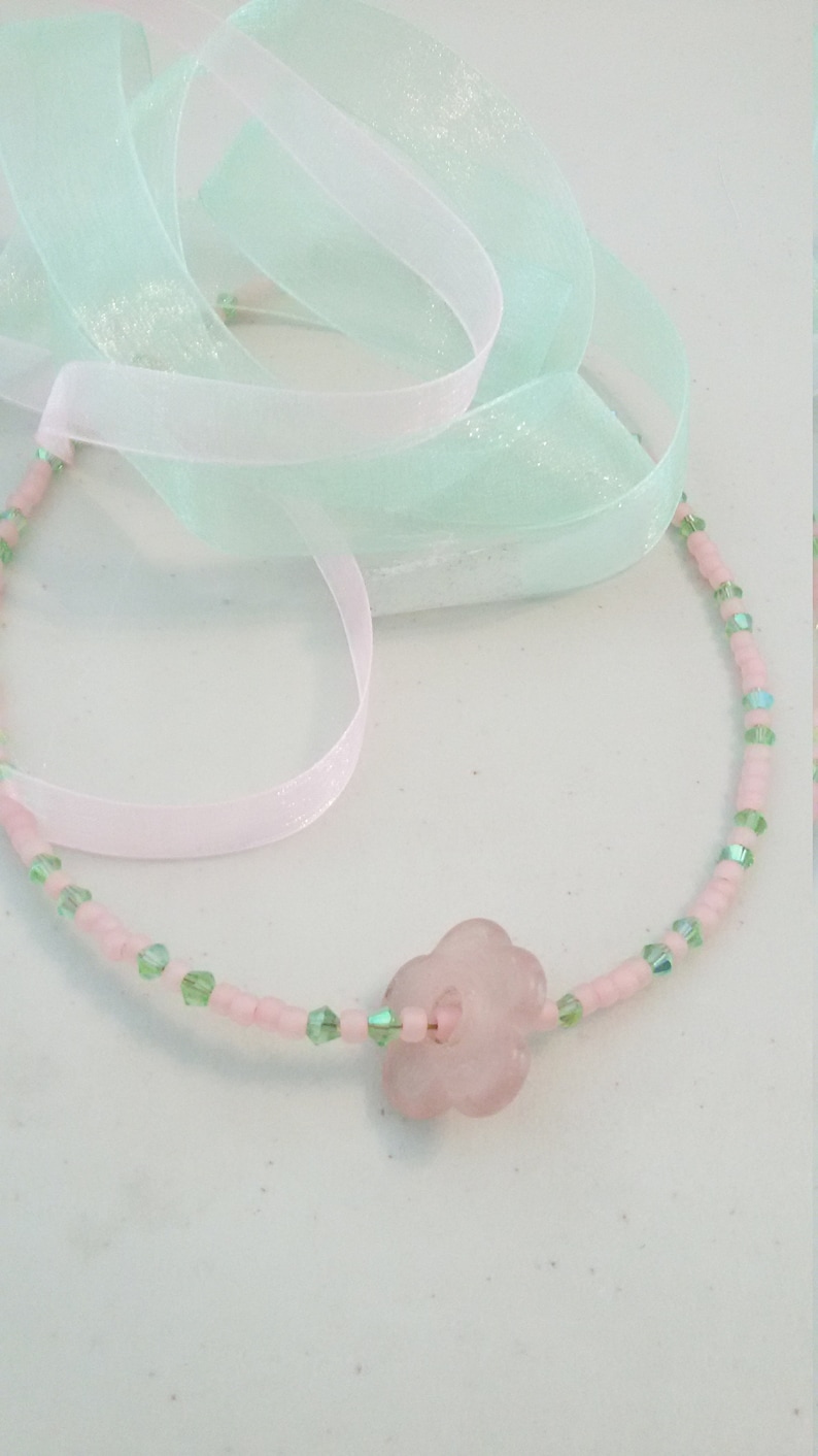 A pale pink quartz flower serves as the pendant. Light pink seed beads with green crystals Sweet pink and green choker