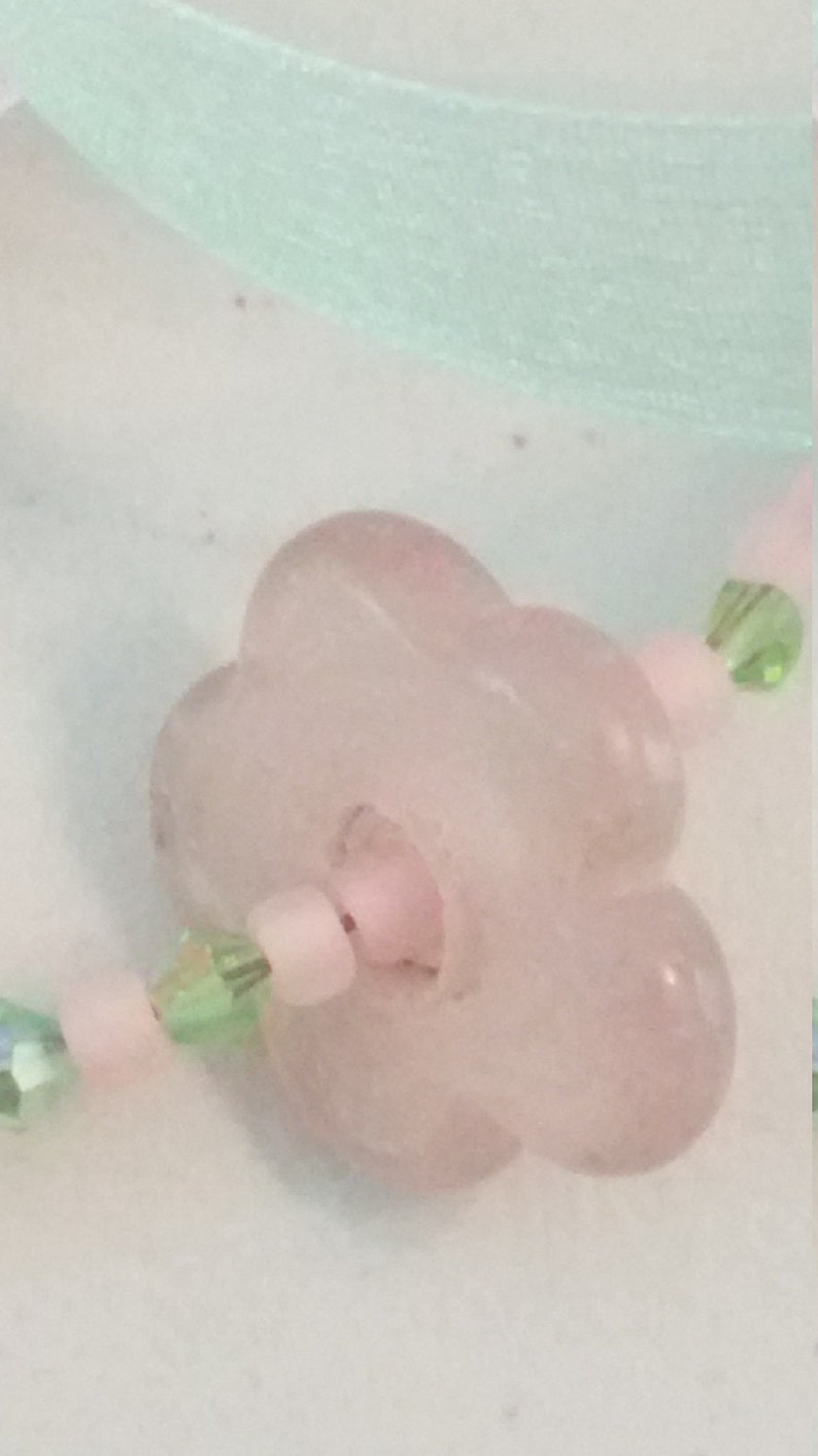 A pale pink quartz flower serves as the pendant. Light pink seed beads with green crystals Sweet pink and green choker