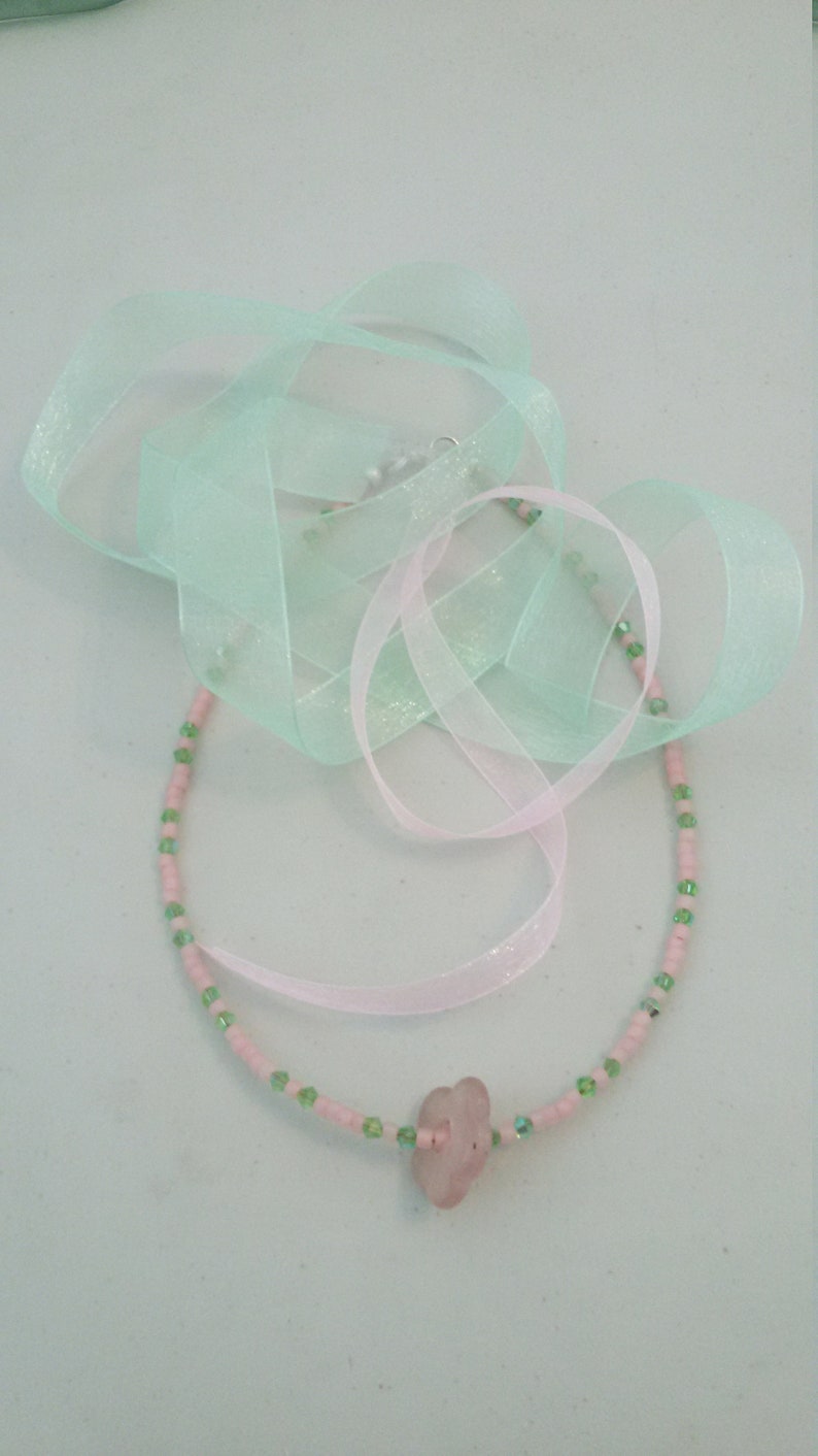 A pale pink quartz flower serves as the pendant. Light pink seed beads with green crystals Sweet pink and green choker