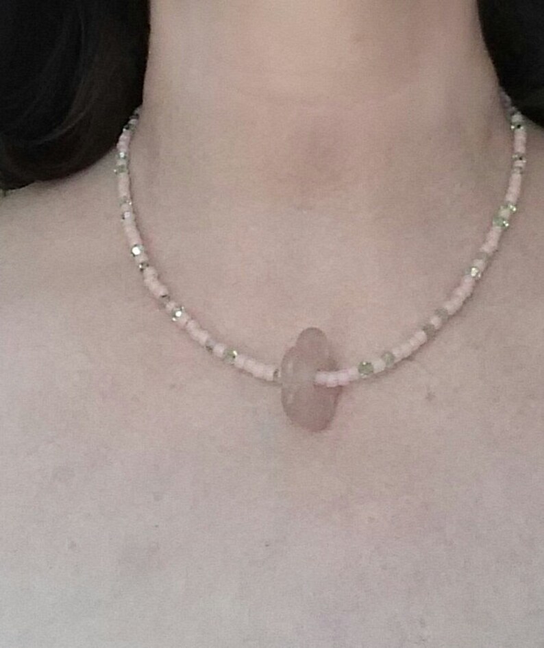 A pale pink quartz flower serves as the pendant. Light pink seed beads with green crystals Sweet pink and green choker