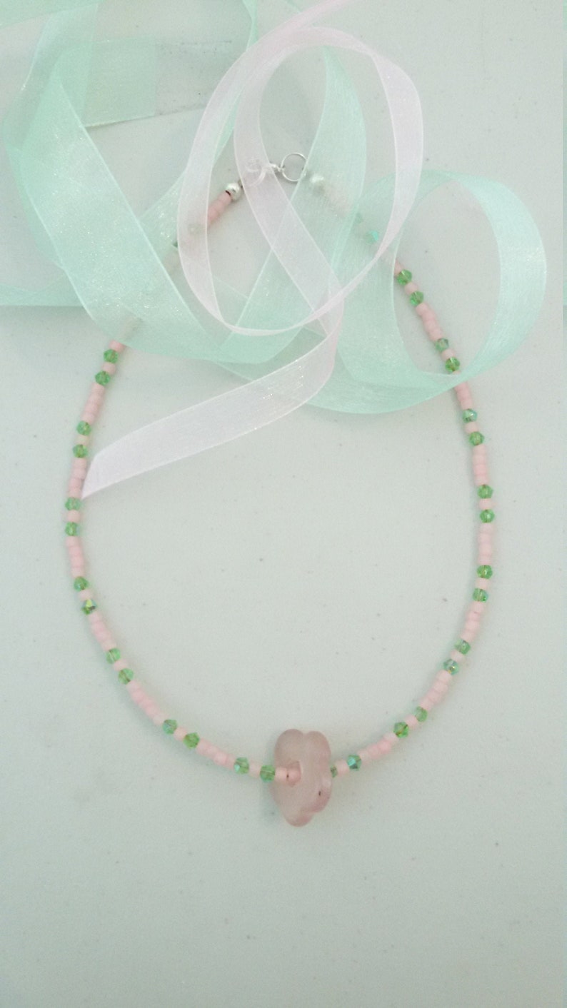 A pale pink quartz flower serves as the pendant. Light pink seed beads with green crystals Sweet pink and green choker