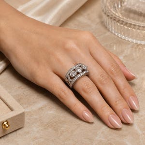 A close-up of a hand wearing a large, ornate ring with multiple diamonds.