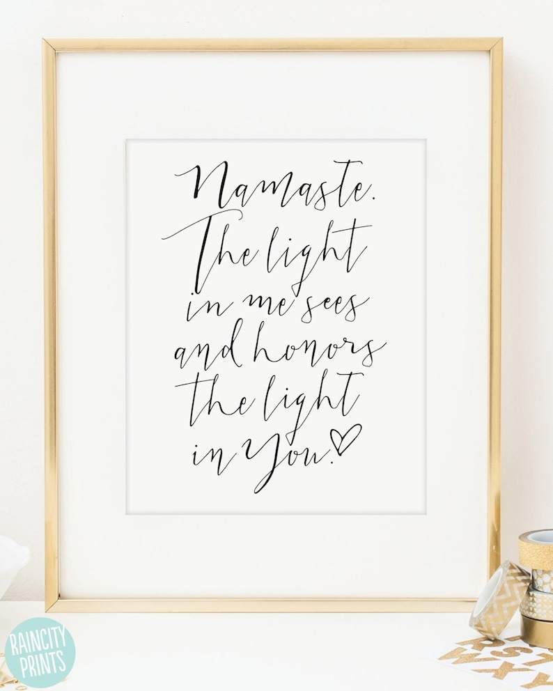 May include: A framed print with the words "Namaste. The light in me sees and honors the light in You." in elegant black script on a white background. The frame is gold-colored.