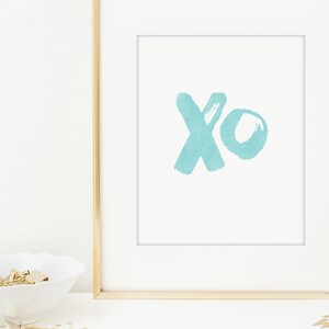 May include: A framed print with a light blue watercolor design of the letters "xo" on a white background.